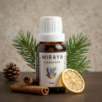 Miraya essential oil bottle with pine branches, cinnamon sticks, and a lemon slice on a wooden surface.